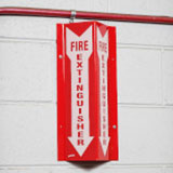 A high-visibility sign attached to a wall. It says "Fire extinguisher." It's V-shaped so that it can be seen from all angles.