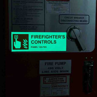 A glowing sign in a dark room that says 'firefighter controls.'