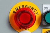 A raised label panel wrapped around the outside of an emergency stop button.