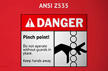 An ANSI Z535 sign. It has a red header that says "Danger" and a pictogram depicting fingers getting pinched in a machine.