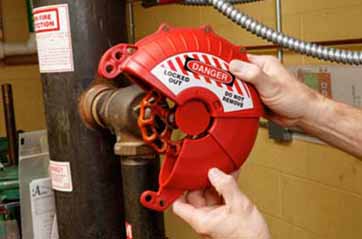 A person puts a circular lockout tagout device over a round valve handle.