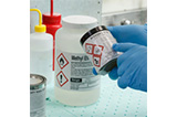 A lab technician points to text on a hazard label. 