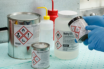 Various containers filled with chemicals are labeled according to hazard communication standards.