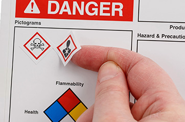 A person applies a pictogram to a danger label.
