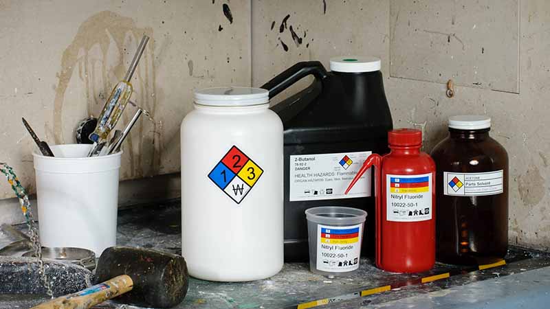 A variety of different sized and shaped containers containing chemicals that are identified by NFPA and HMIS labels.