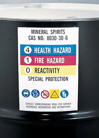 A black barrel with an HMIS/HMIG label showing a Health Hazard level of 4, Fire Hazard of 1, Reactivity of 0 and PPE needed for handling.