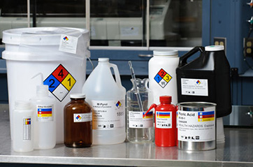 A variety of different sized and shaped containers containing chemicals that are identified by NFPA and HMIS labels.