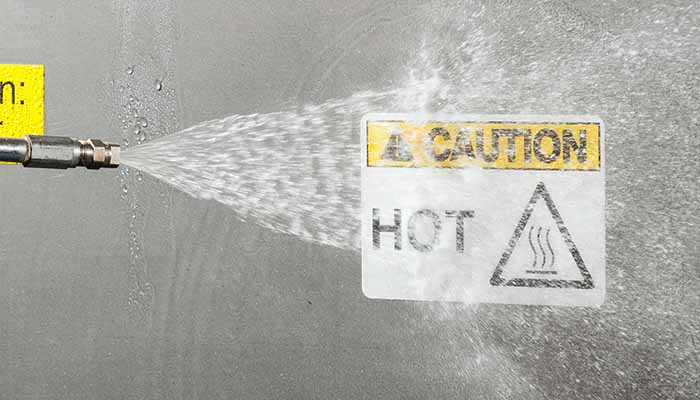 An acrylic adhesive label getting doused by hot water from a hose.