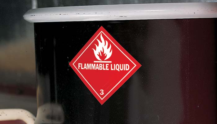 An acrylic based adhesive flammable liquid label attached to the front of a drum barrel.