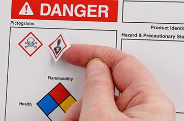 A worker adds HCS Pictograms to an HCS compliant label.