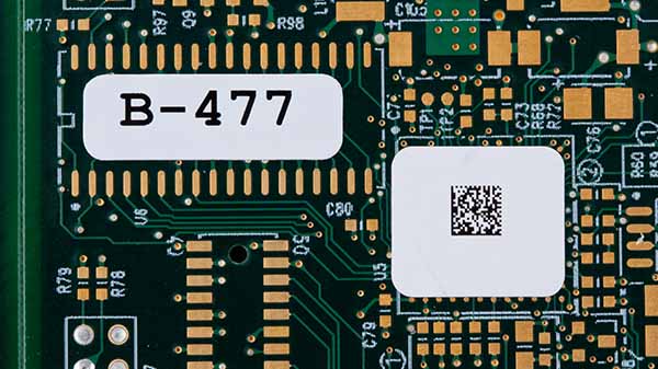Two labels on a microchip. One says "B-477," and the other has a QR code.
