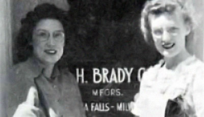 Two women standing in front of the W. H. Brady Company storefront in Menomonee Falls, Wisconsin. 