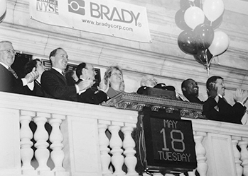 A group of jubilant Brady employees celebrating the company's transition to a public entity at the New York Stock Exchange on May 18th, 1984.
