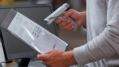 A person scanning a manufacturing document with an RFID scanner.