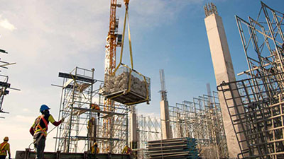 A worker keeps a pallet of materials steady as it's lowered to the ground.
