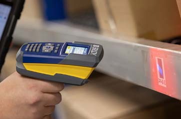 A warehouse worker takes inventory of shelved products using a V4500 Brady barcode scanner.
