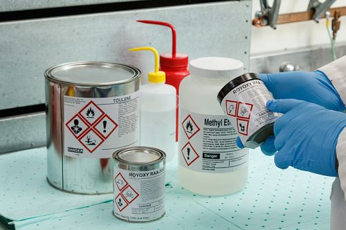 A person attaches a QR code label to a beaker.