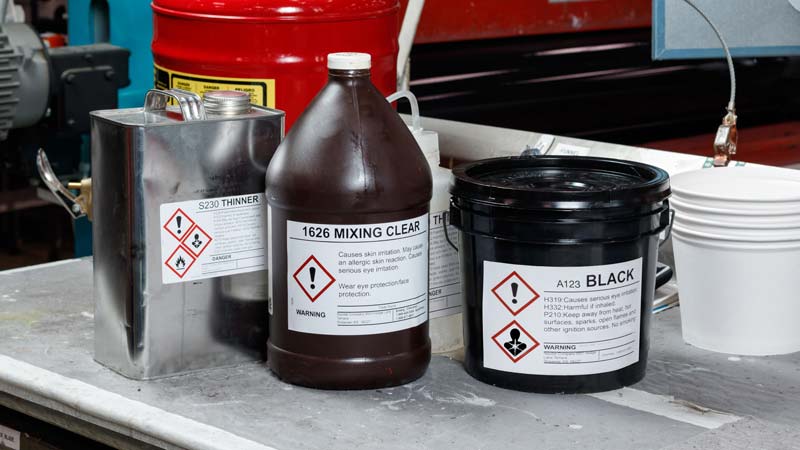 Three secondary containers with different HazCom and GHS labels, specific to the chemicals they contain.