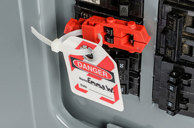 A lockout tag securely attached to a fuse within an electrical panel, serving as a critical measure for ensuring safety.