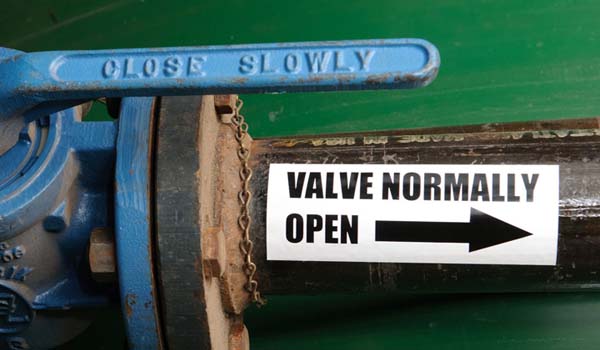 A blue shut-off valve with a label stating "valve normally open" and an arrow pointing up.
