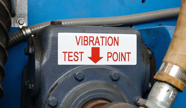 An up-close image of a manufacturing machine part with a sign displaying "vibration test point".