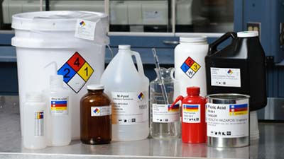 A variety of chemical containers with hazcom labels.