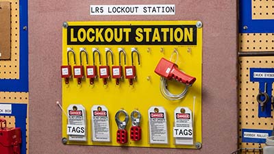 A lockout station with labeled padlocks and tags.