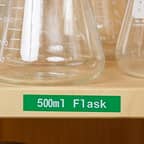 A green label with the text 50ml Flasks identifying a shelf laboratory flasks.