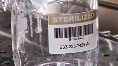 A glass container with a barcode label that identifies it as sterilized.