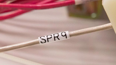 A tan wire with a white identification label within a wiring harness.