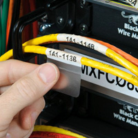 A person attaches wrap-around labels to wires.