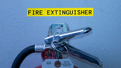 A reflective label stands out brightly in a dark room to indentify a fire extinguisher.