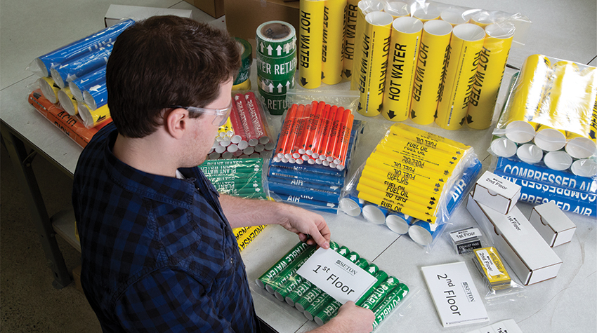 A Brady safety services technician carefully packaging a kit of pipe markers custom made for a construction project.