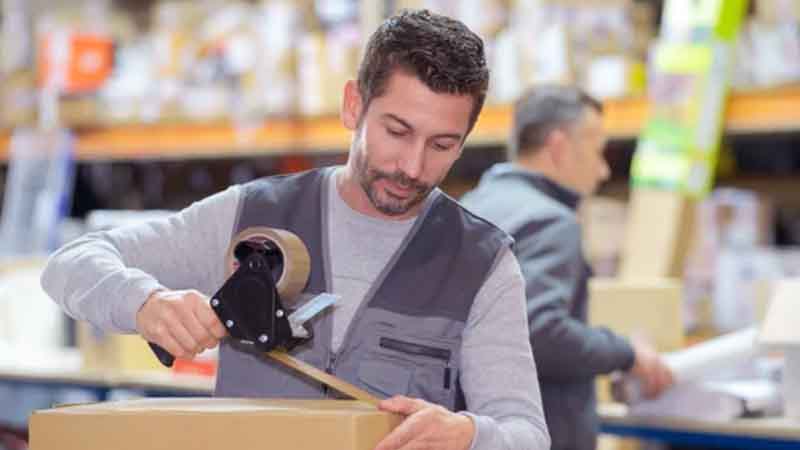 A warehouse worker seals a cardboard box.