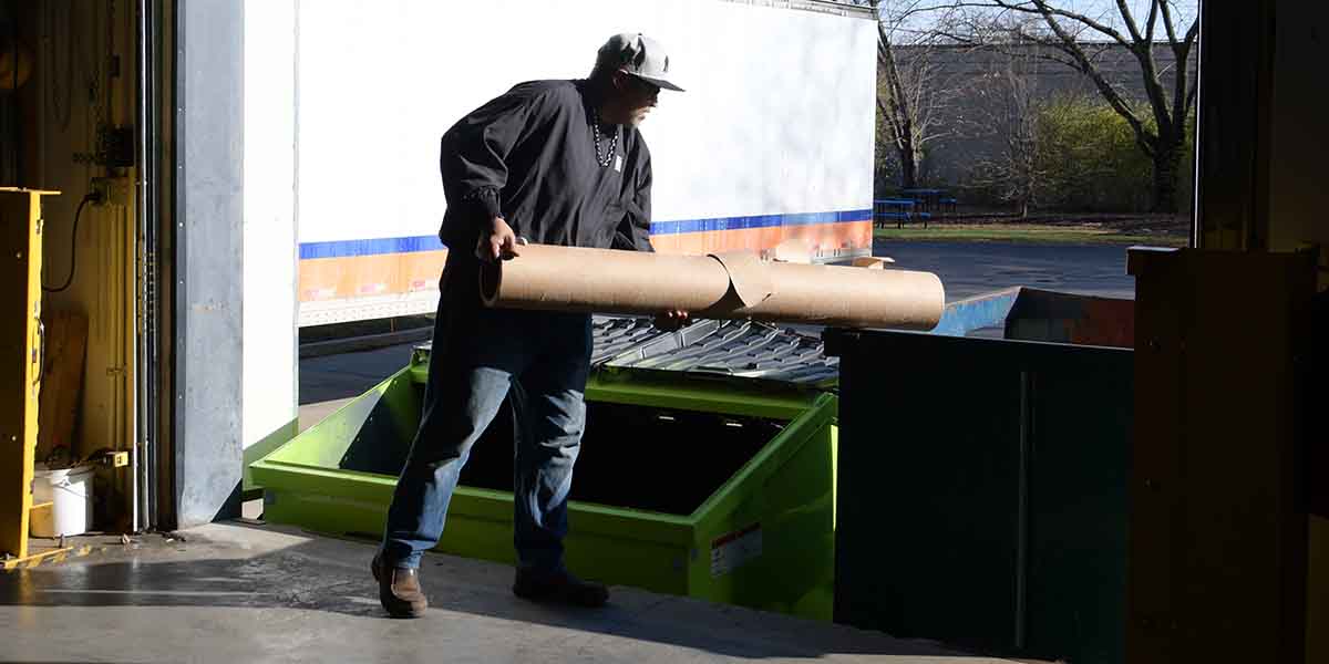 A worker recycling a large cardboard core for roll material.
