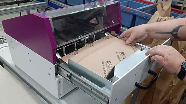 A Wave Wrap machine being loaded with recycled cardboard in order to create packaging for another product.