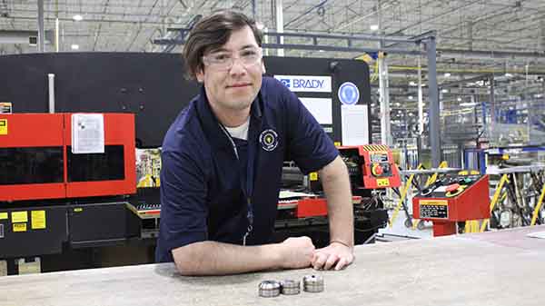 An employee posing proudly in front of repaired rotary dies.