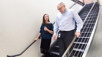 Two employees conversing while descending the stairs.