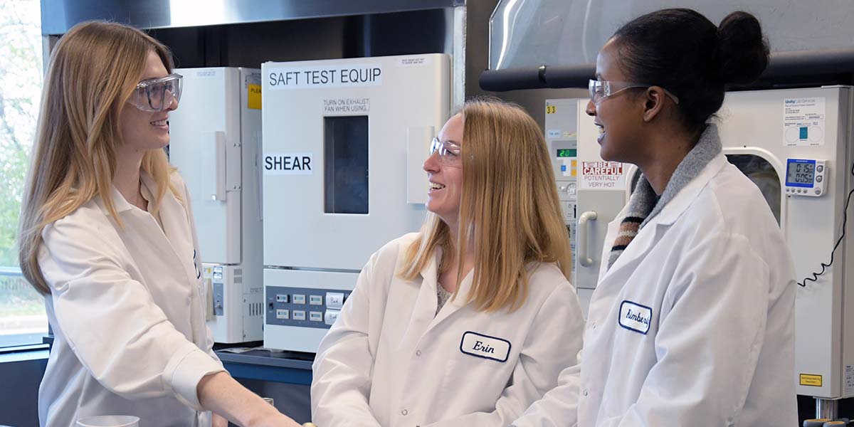Three women working in the Brady material engineering department, happily engaged in conversation.