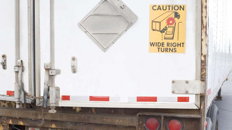 A close-up of the back of a trailer that has DOT-compliant red and white reflective tape.