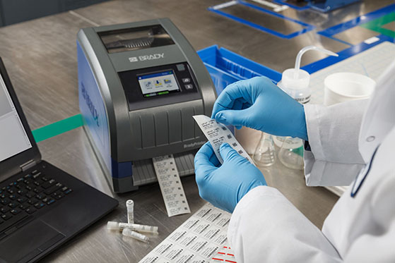 Scientist in a laboratory operating a Brady printer to create specimen labels.