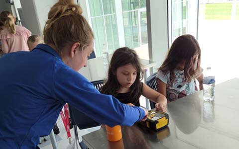 Erin and two students examining a small printing machine.